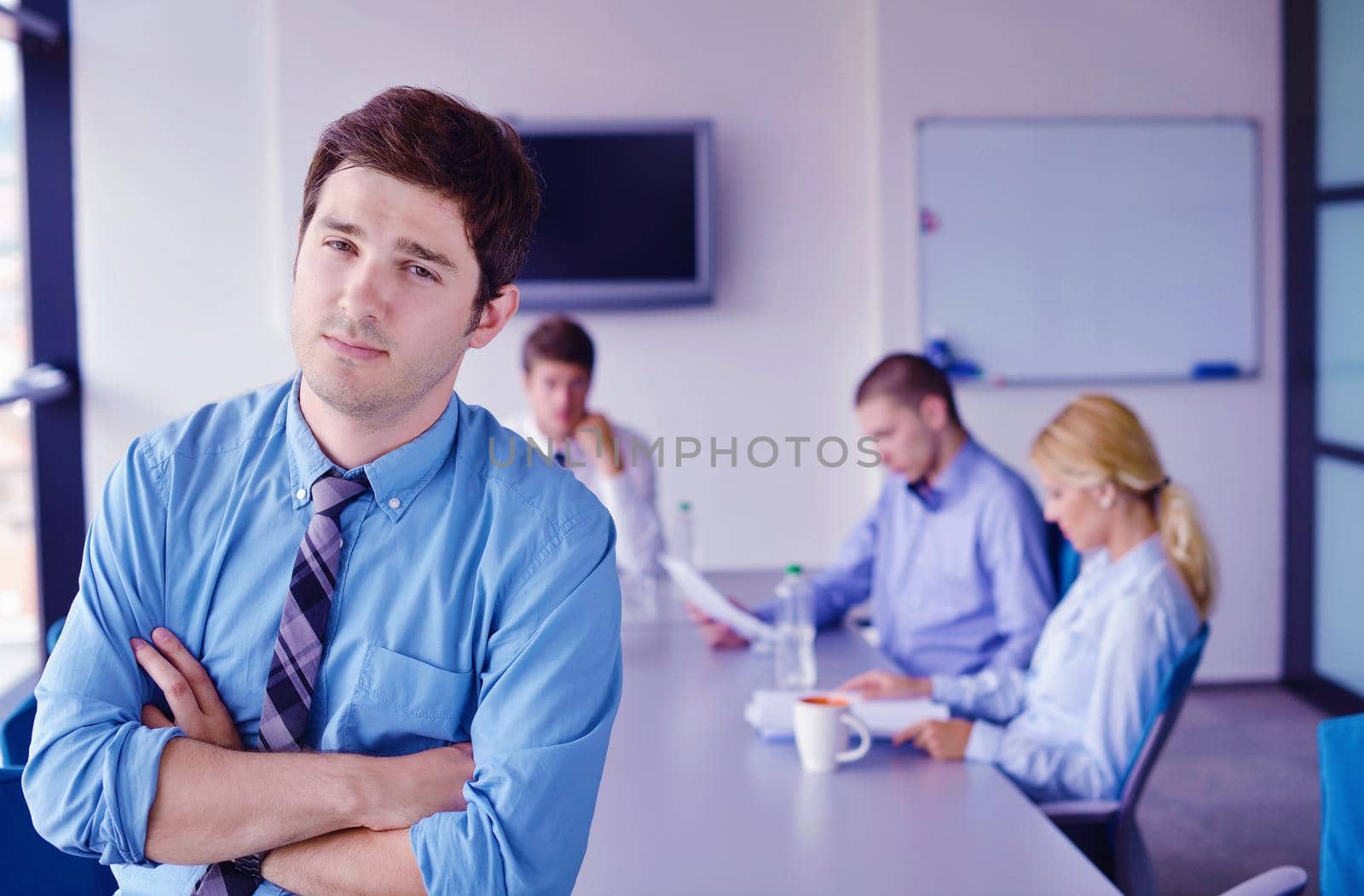 Portrait of a handsome young  business man  on a meeting in offce with colleagues in background