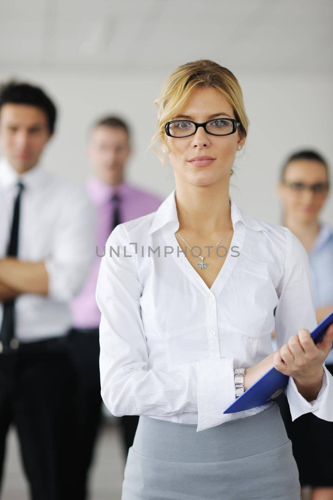 Successful business woman standing with her staff in background at modern bright office