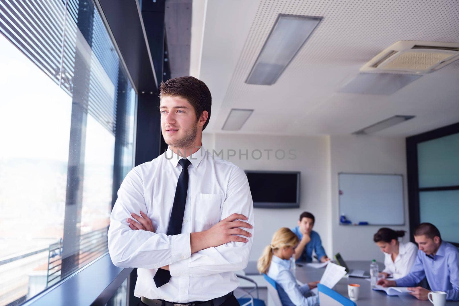 Portrait of a handsome young  business man  on a meeting in offce with colleagues in background