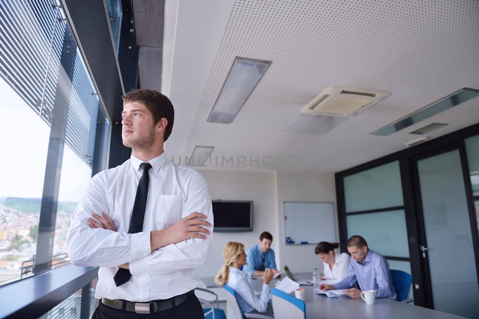 business man  on a meeting in offce with colleagues in background by dotshock