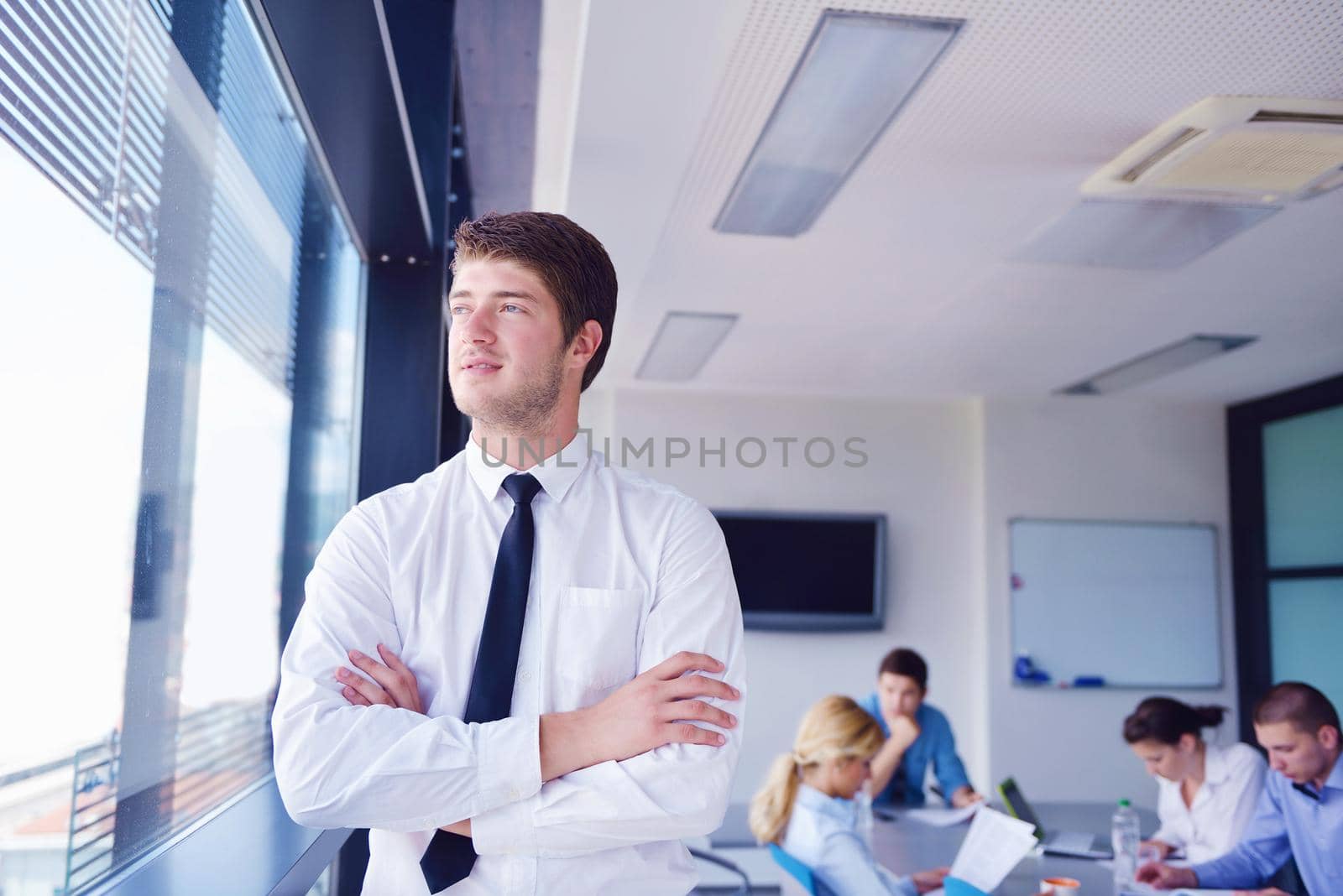 business man  on a meeting in offce with colleagues in background by dotshock