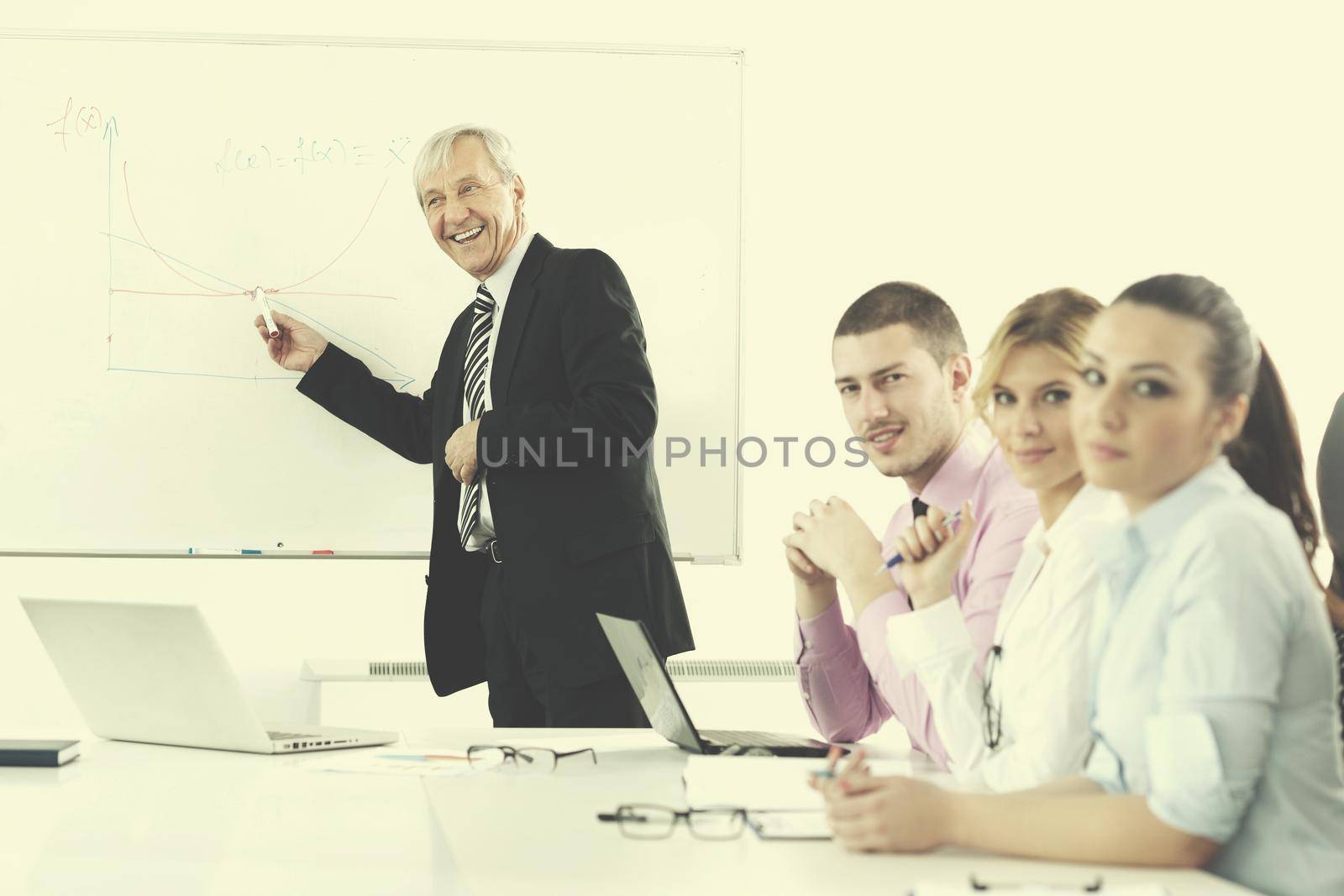 Senior male business man giving a presentation at a  meeting at modern light office on a table board