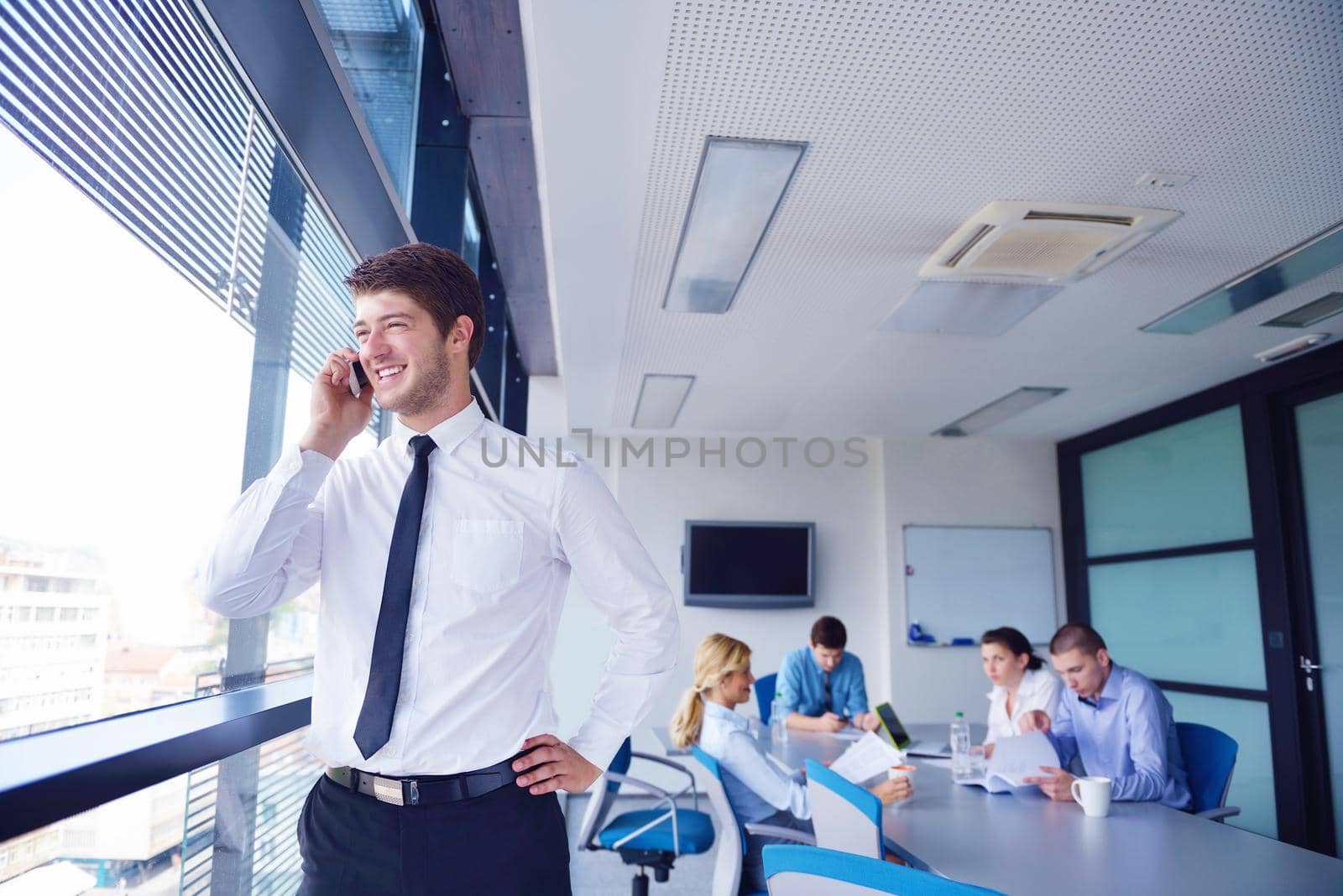 Portrait of a handsome young  business man  on a meeting in offce with colleagues in background