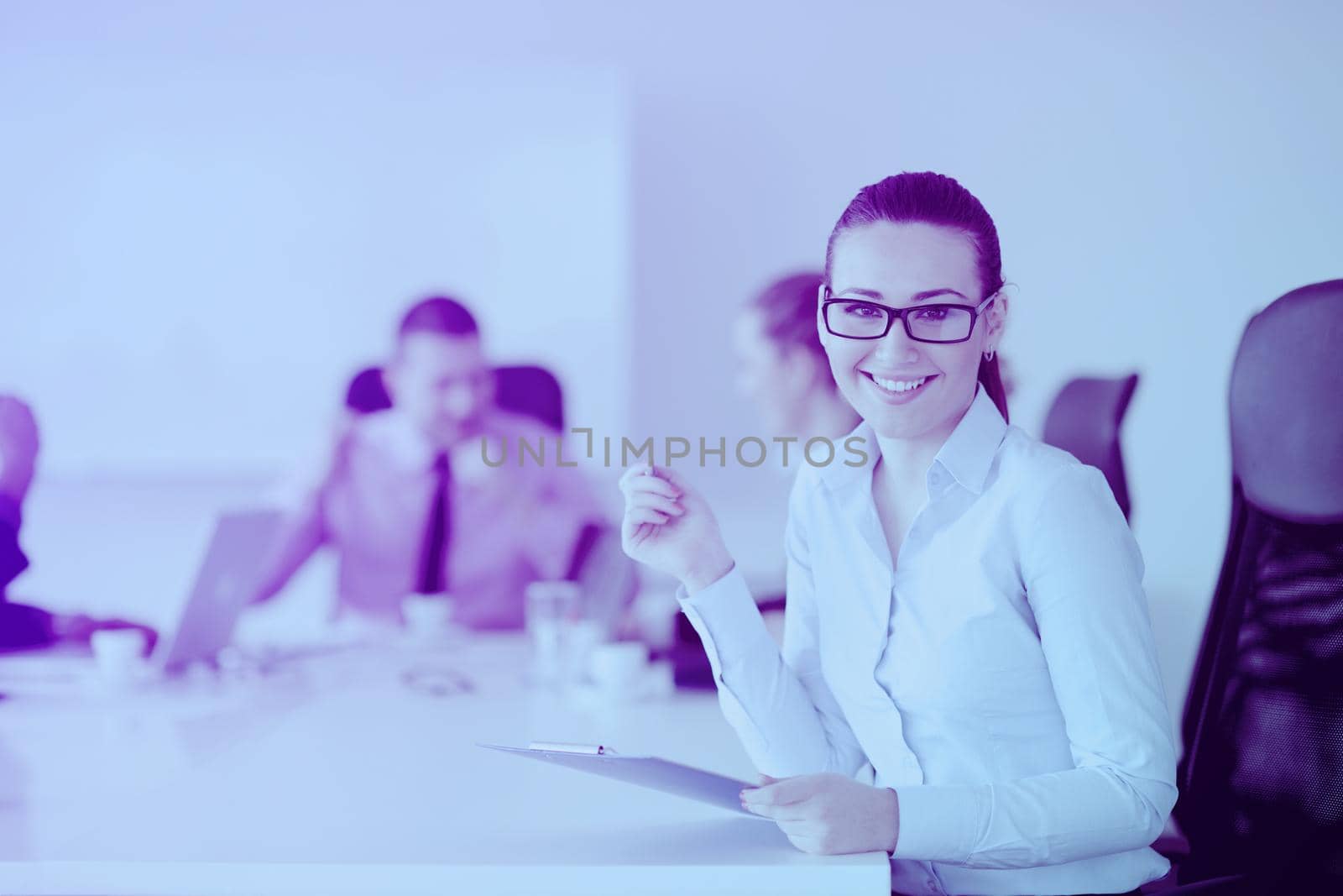 Successful business woman standing with her staff in background at modern bright office