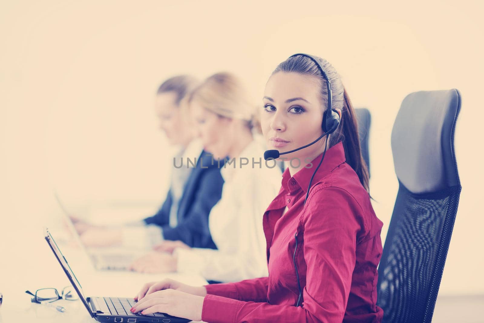 Pretty young business woman group with headphones smiling at you against white background