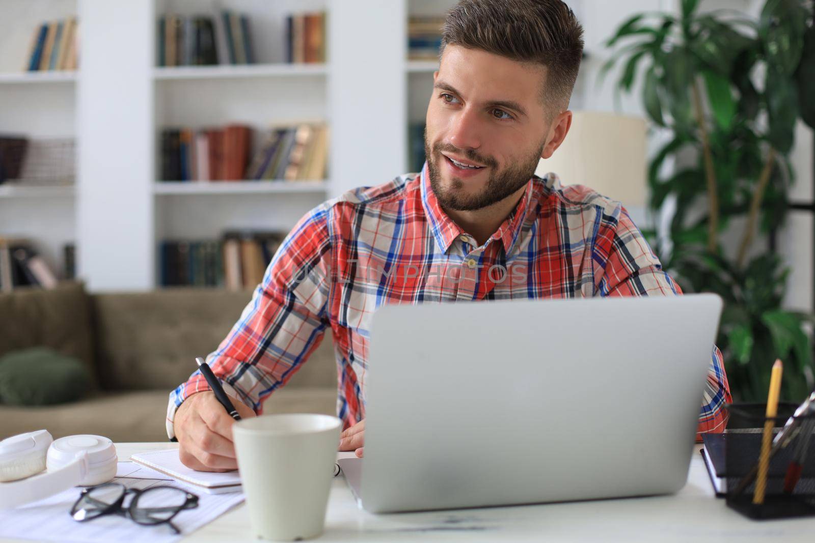 Happy young business man is analizing financial documents from home during self isolation