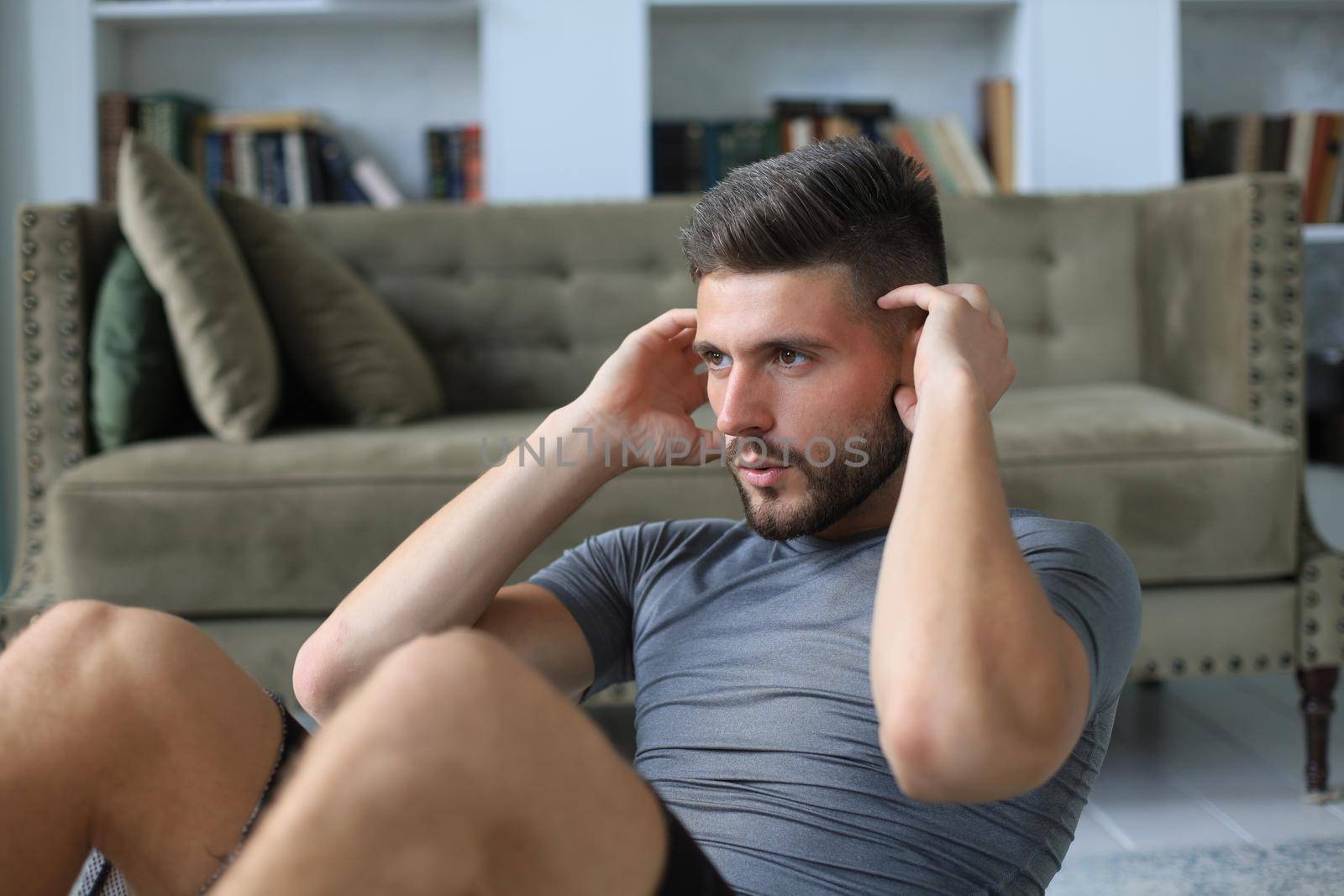 Handsome man doing abs exercises at home during quarantine. Concept of healthy life