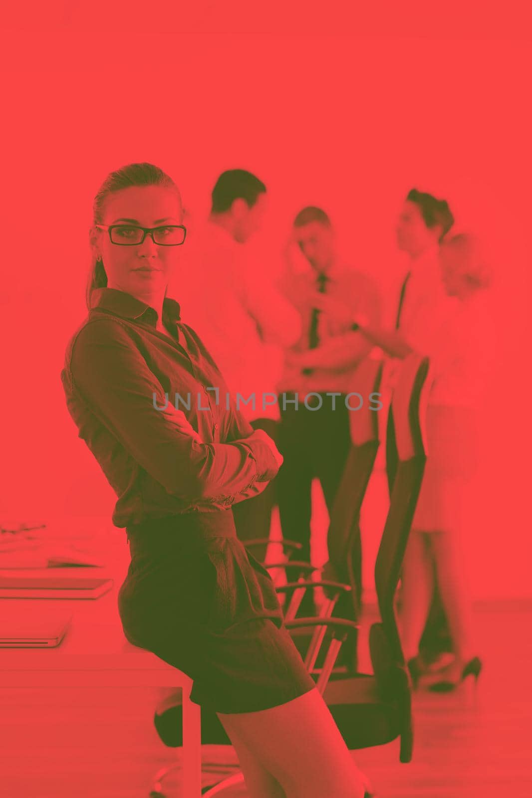 Successful business woman standing with her staff in background at modern bright office