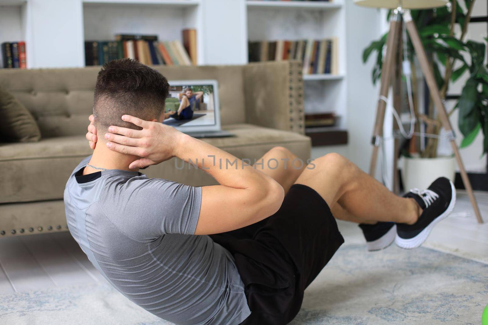 Handsome man doing abs exercises at home during quarantine. Concept of healthy life