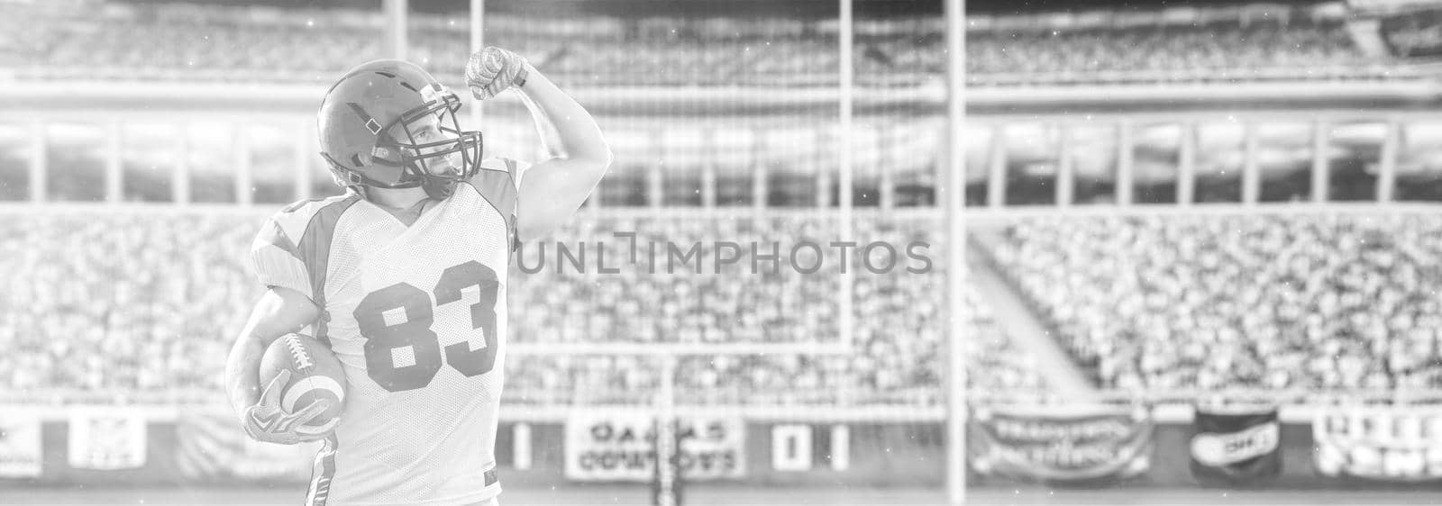 american football player celebrating touchdown on big modern stadium field with lights and flares