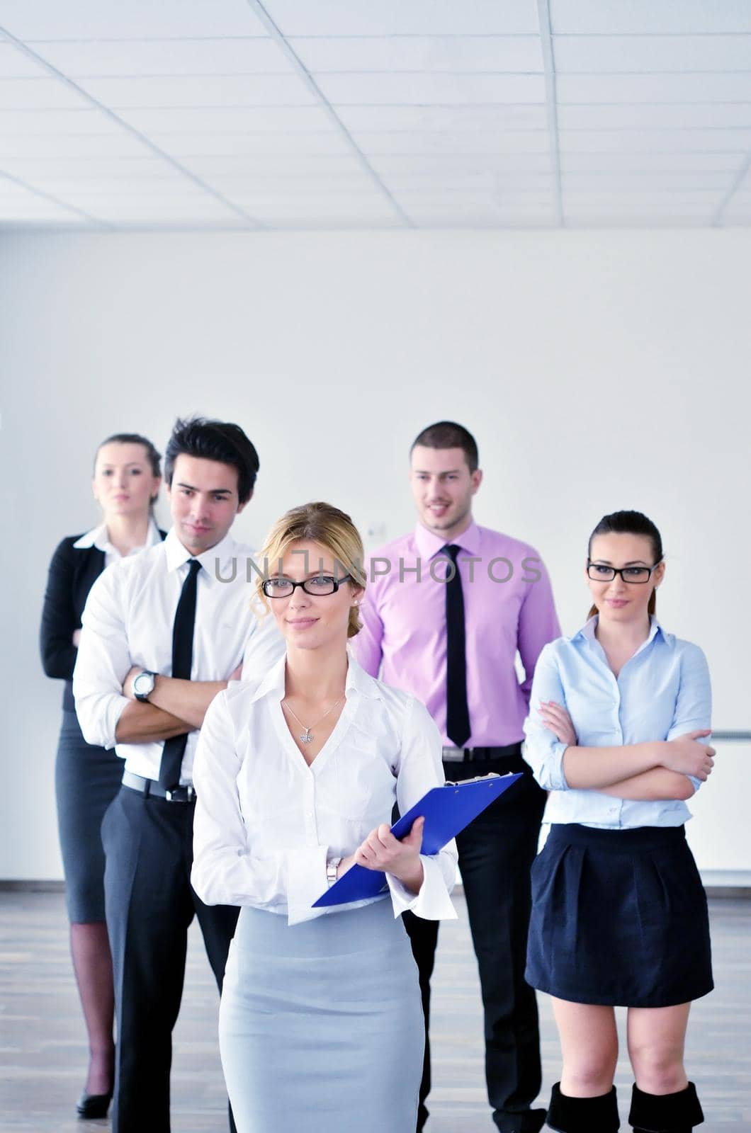 Successful business woman standing with her staff in background at modern bright office