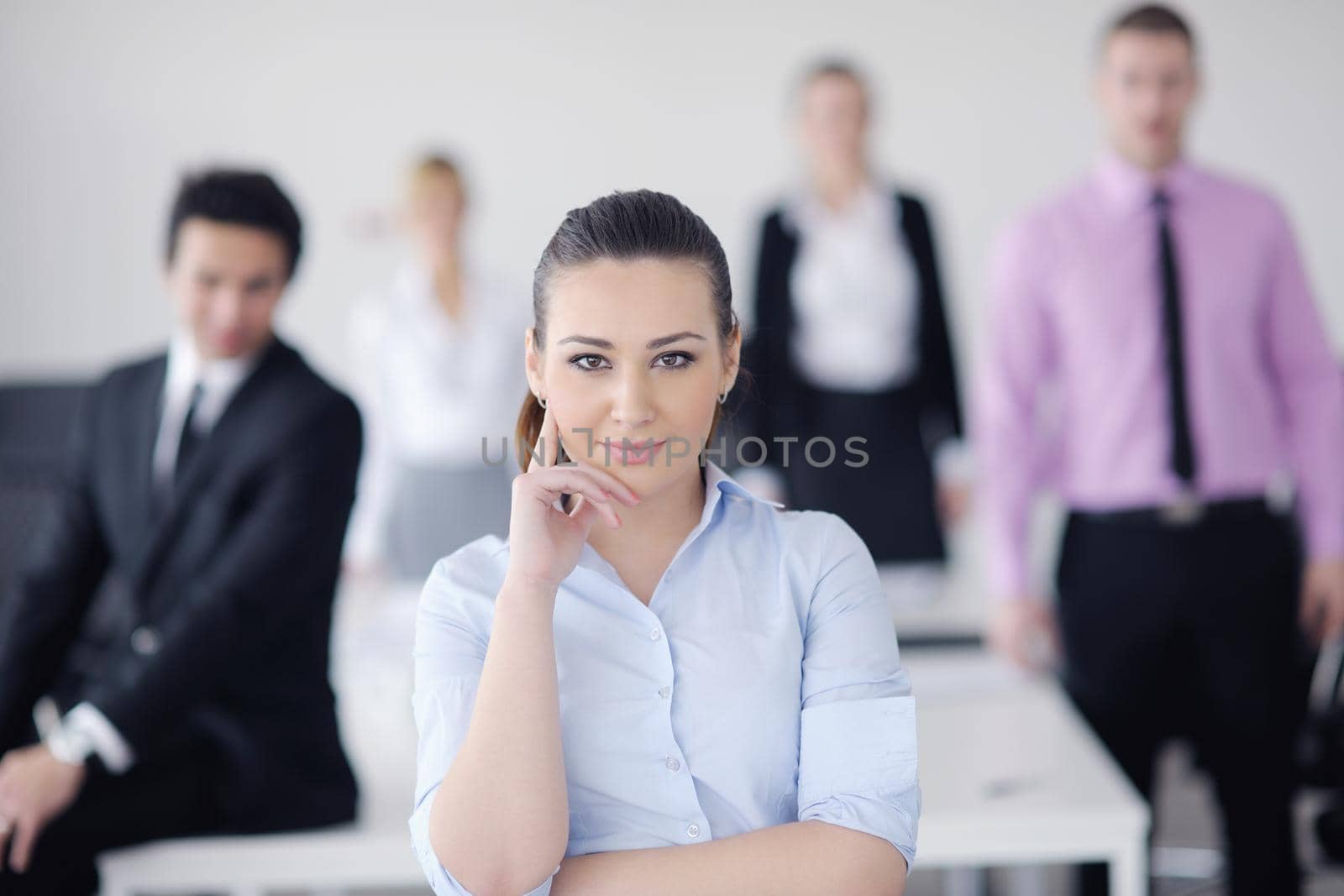 Successful business woman standing with her staff in background at modern bright office