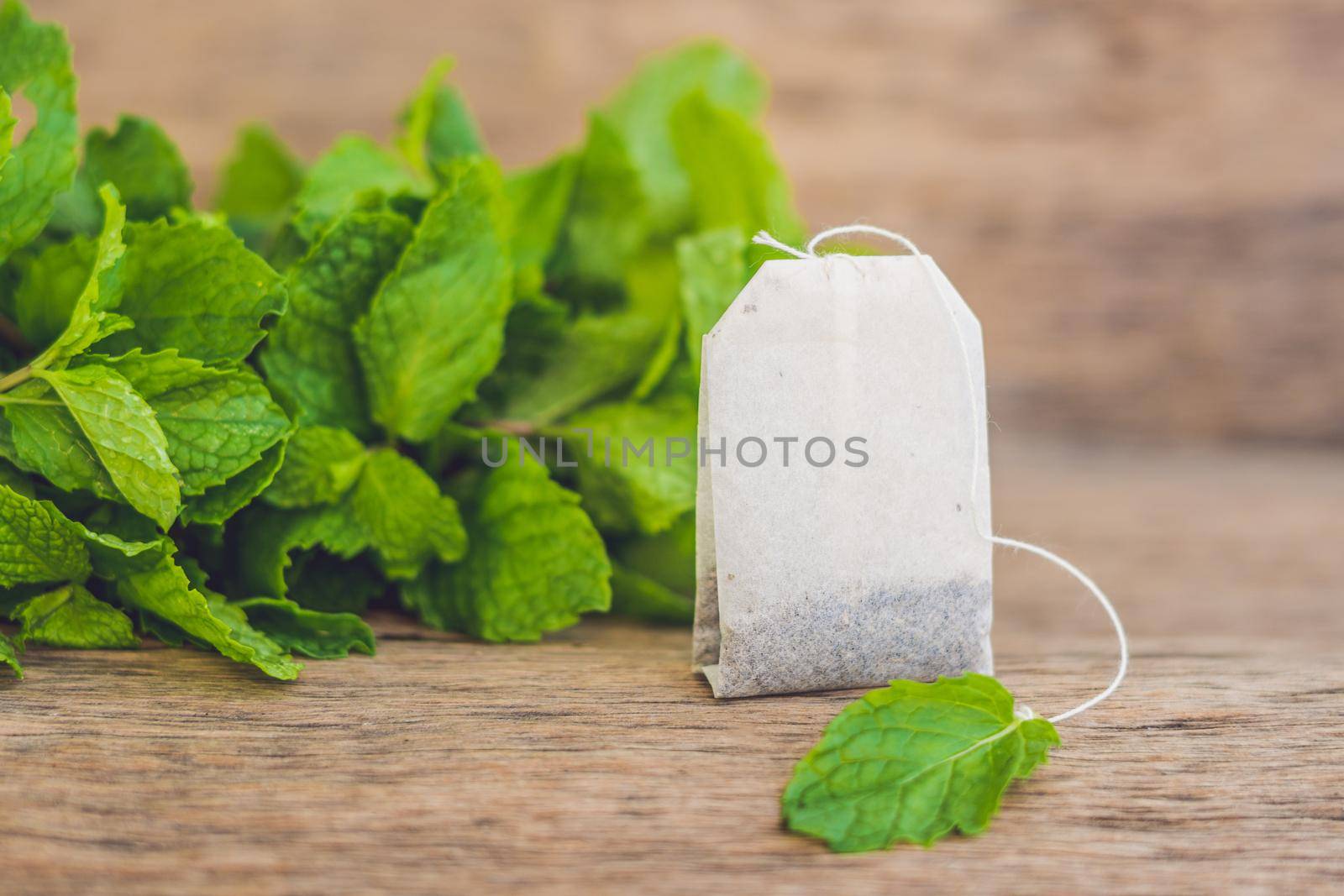 Tea bags on wooden background with fresh melissa, mint. Tea with mint concept.