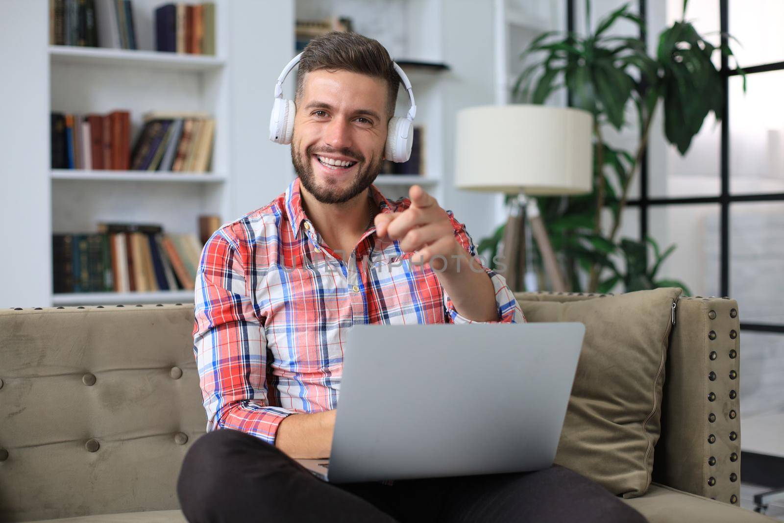 Smiling businessman greeting colleagues in video conference and negotiating distantly from home