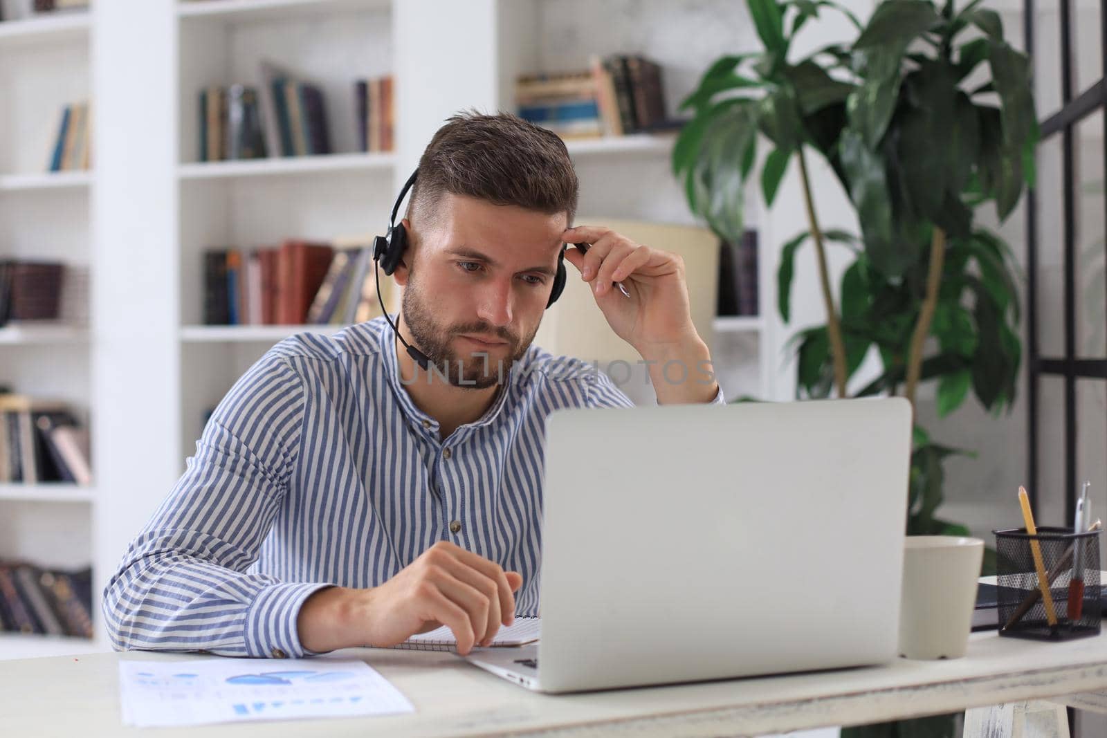 Thoughtful modern business man working using laptop while sitting in the office