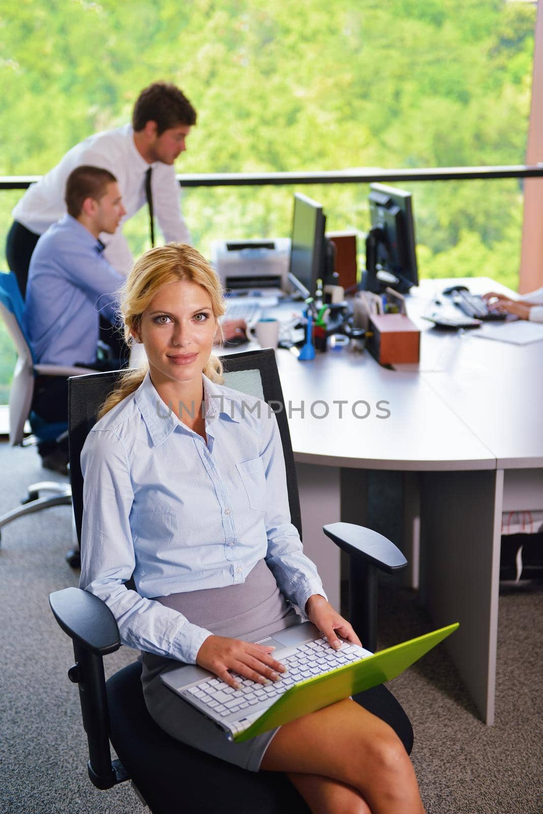 business woman with her staff in background at office by dotshock