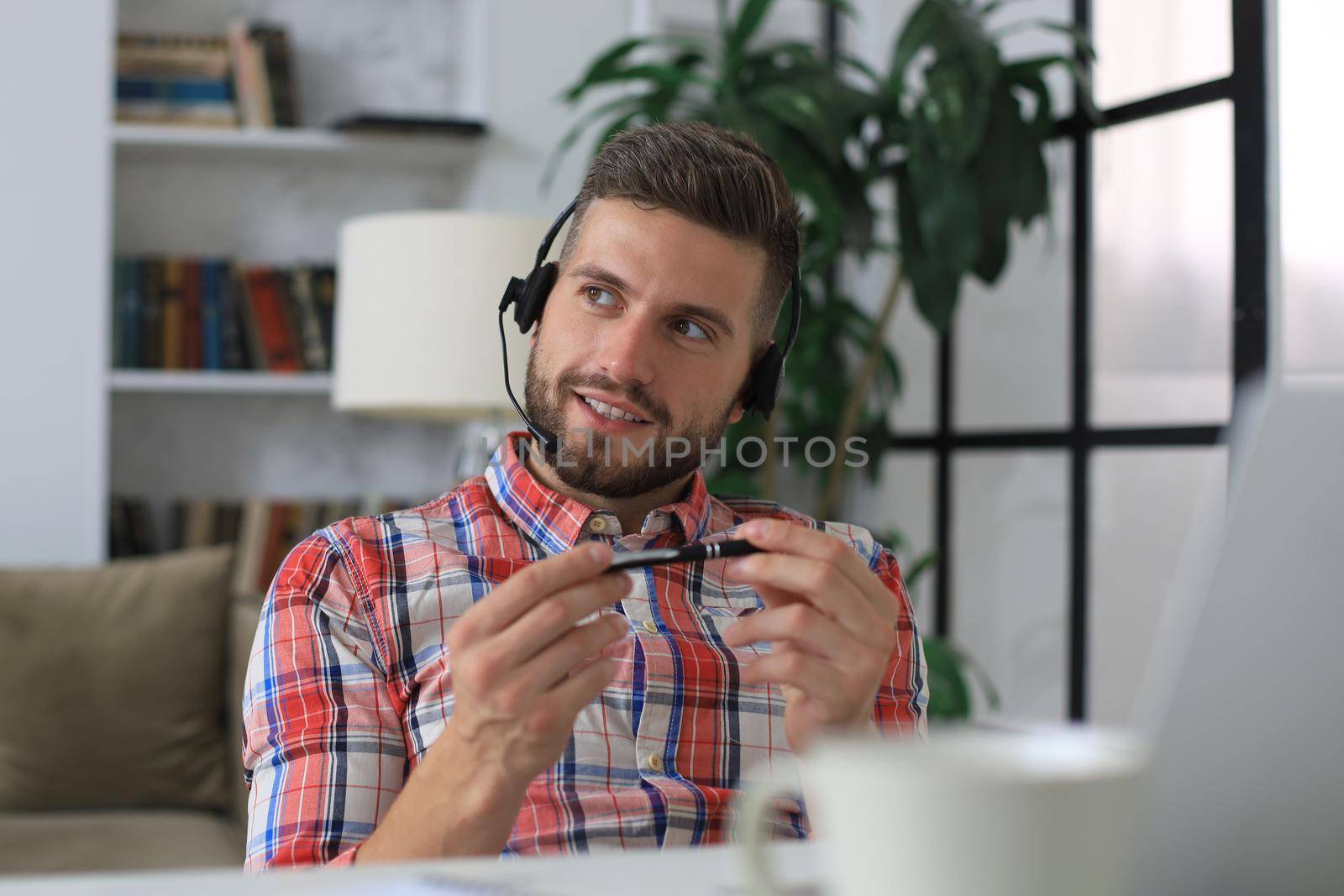 Happy young man in earphones working on laptop from home during self isolation