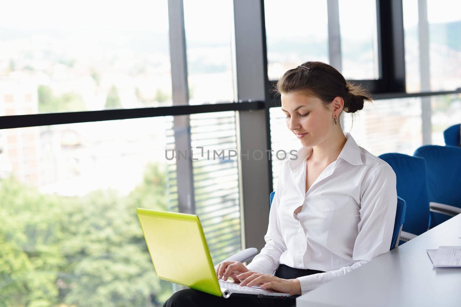 Young pretty business woman with notebook in the bright modern office indoors