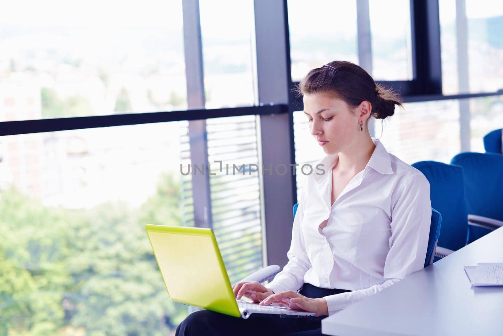 Young pretty business woman with notebook in the bright modern office indoors