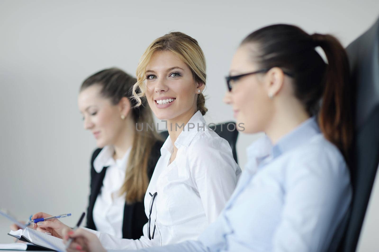 Successful business woman standing with her staff in background at modern bright office