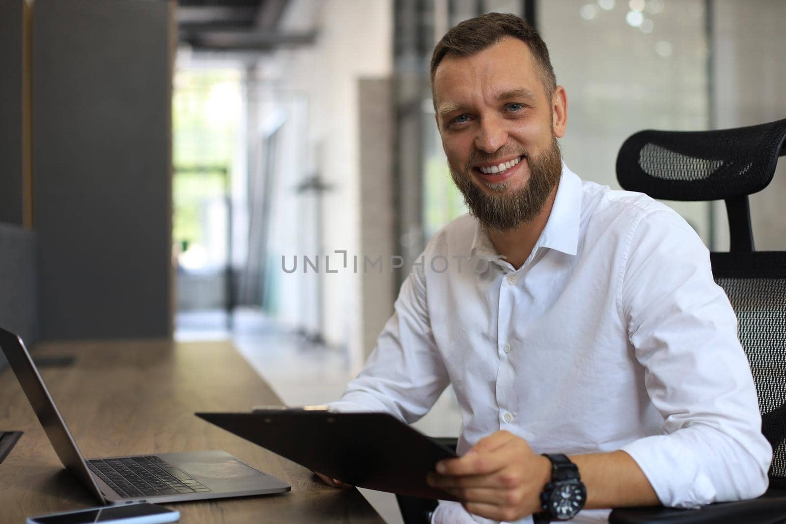 Young man is working with papers while sitting in the office. Successful entrepreneur is studying documents with attentive and concentrated look.