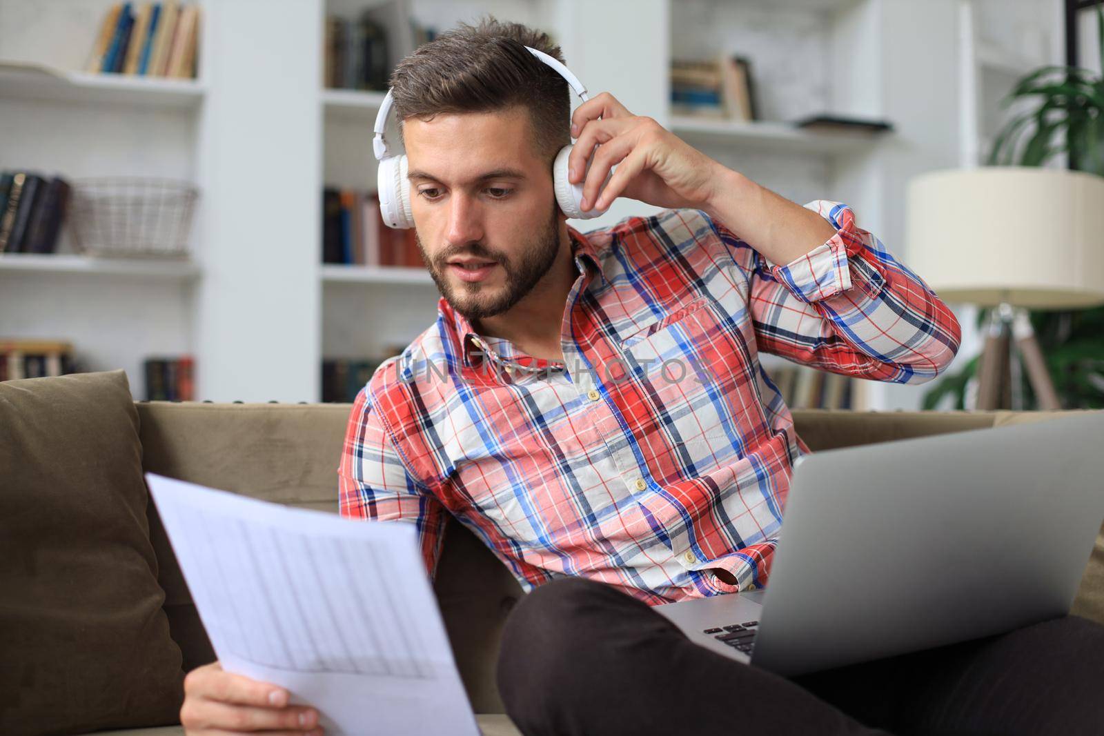 Smiling businessman greeting colleagues in video conference and negotiating distantly from home