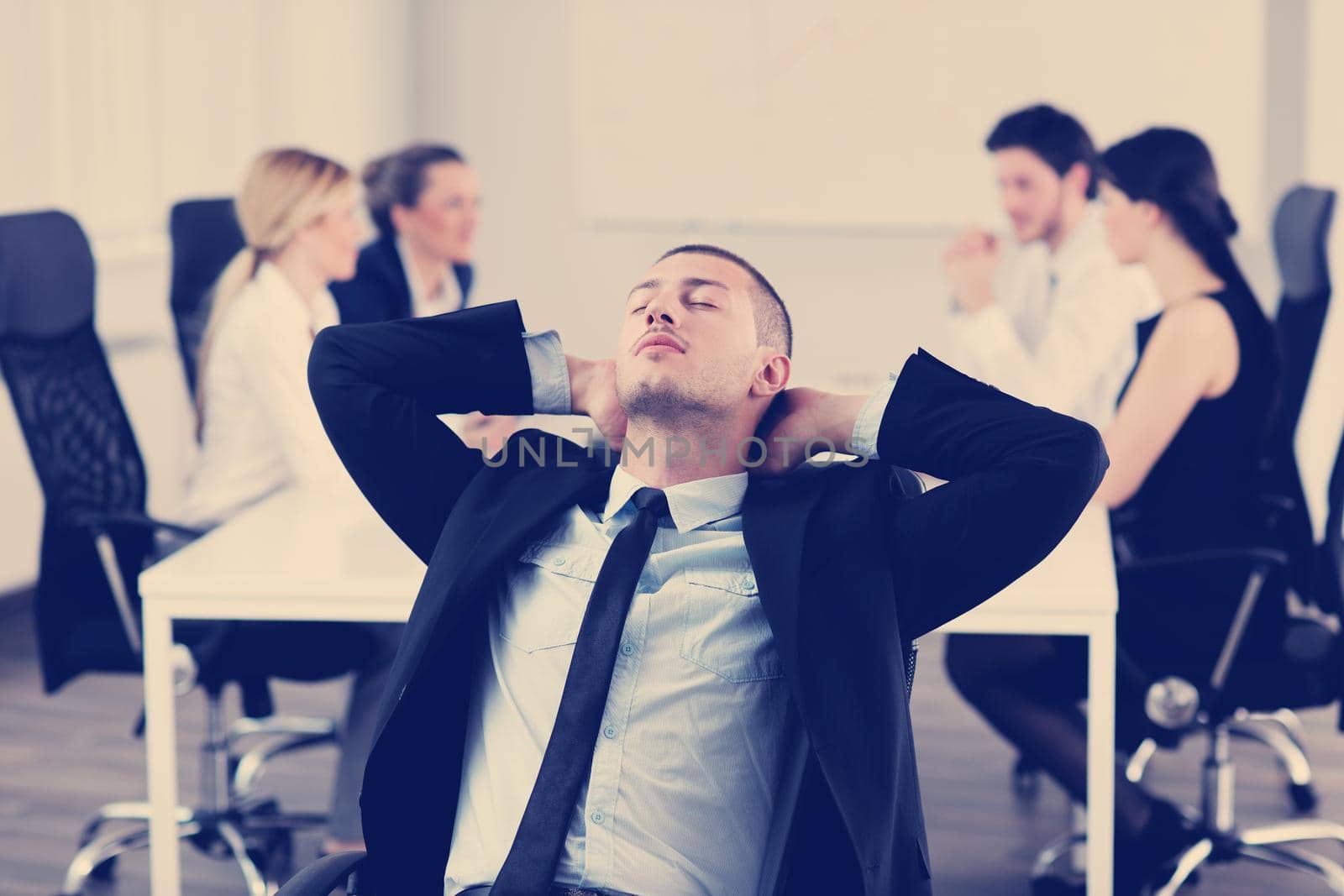 Portrait of a handsome young business man with people  in background at office meeting