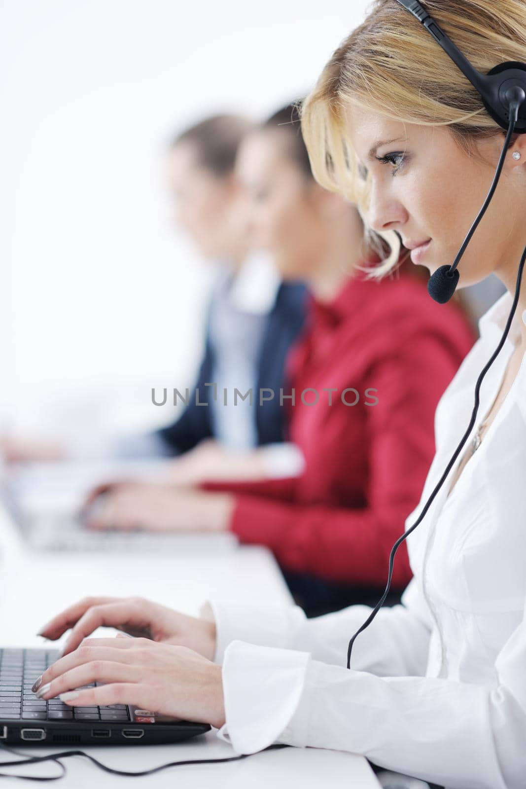 Pretty young business woman group with headphones smiling at you against white background