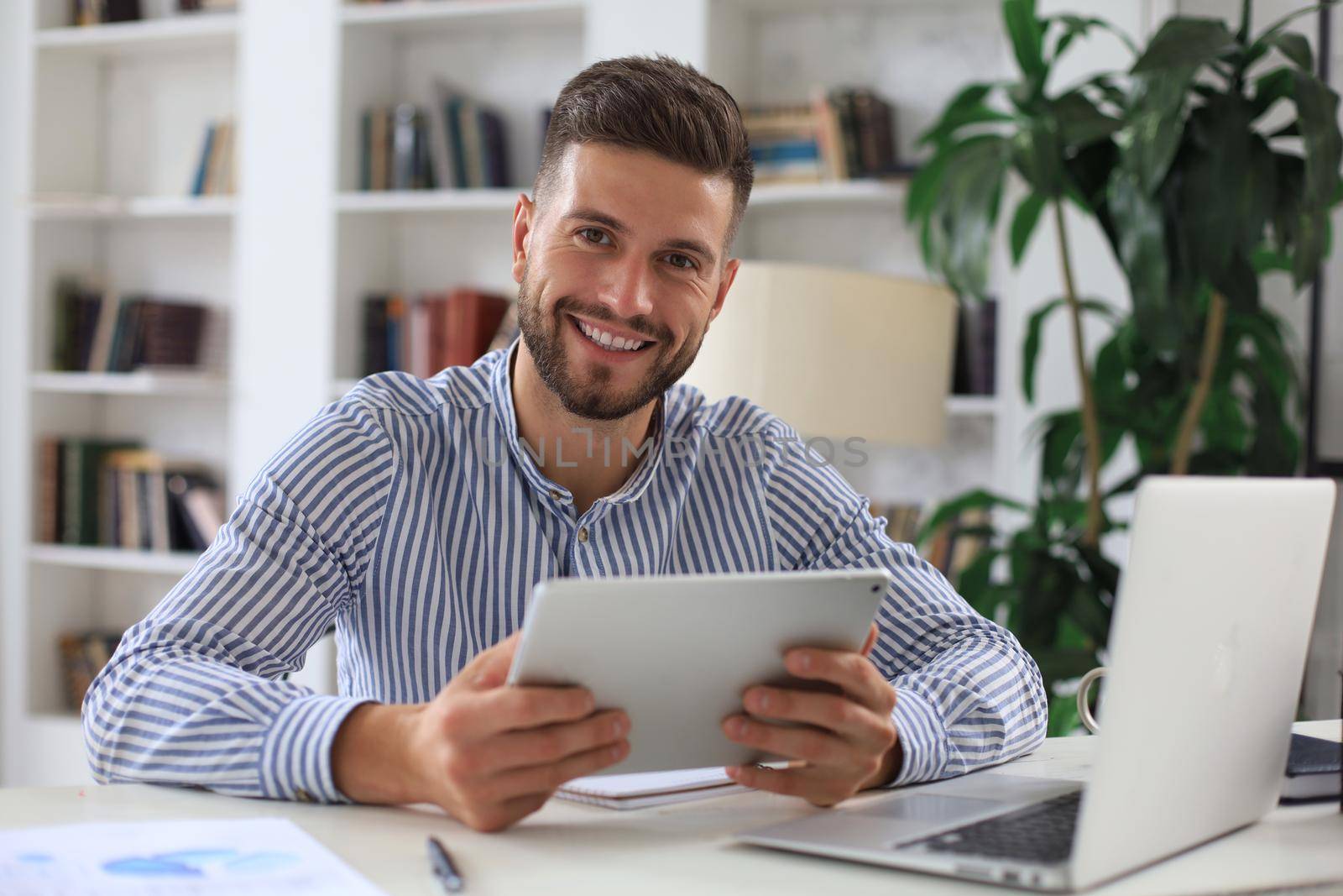 Happy young business man is analizing financial documents from home during self isolation