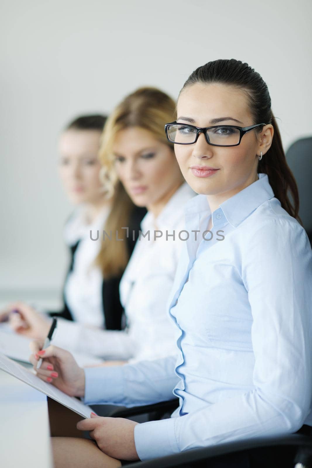 Successful business woman standing with her staff in background at modern bright office