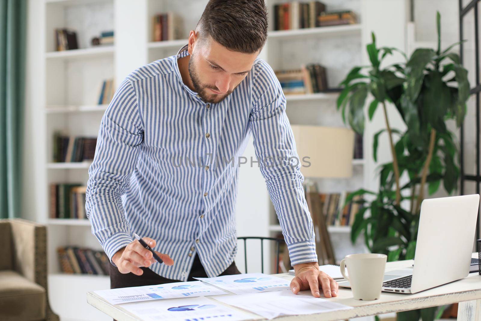 Young modern business man analyzing data using laptop while working in the office