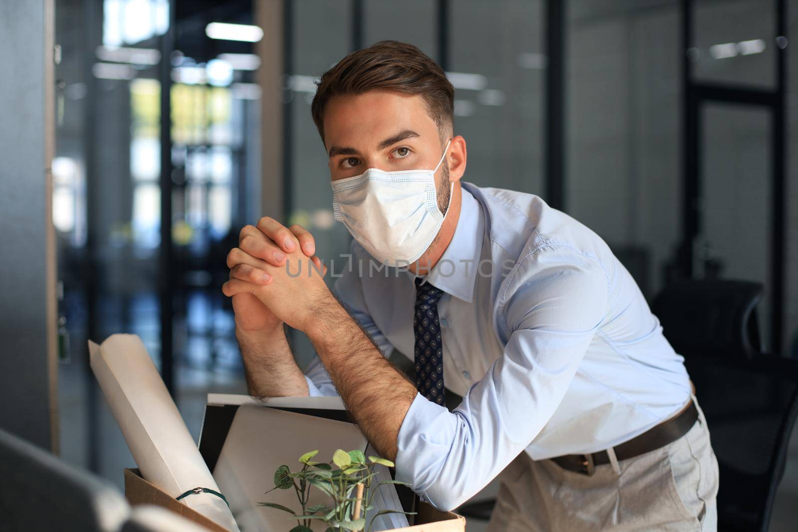 Dismissal employee in an epidemic coronavirus. Sad dismissed worker are taking his office supplies with him from office
