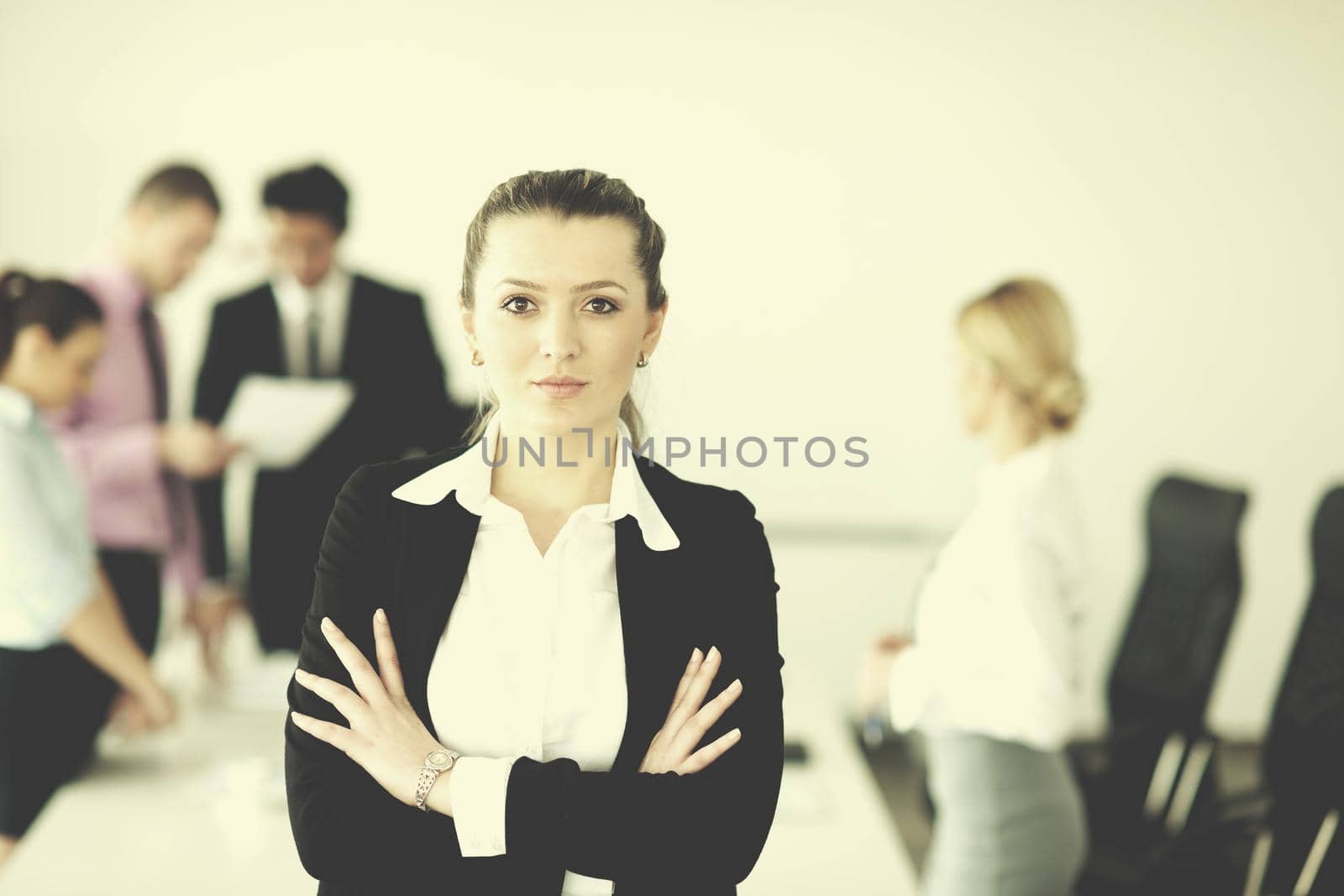 Successful business woman standing with her staff in background at modern bright office