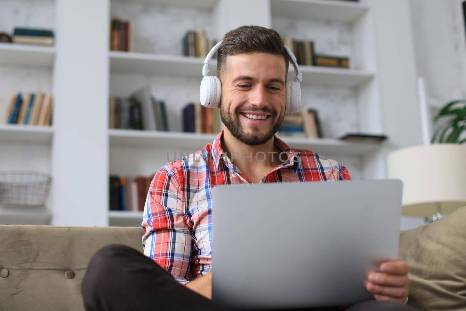 Smiling businessman greeting colleagues in video conference and negotiating distantly from home