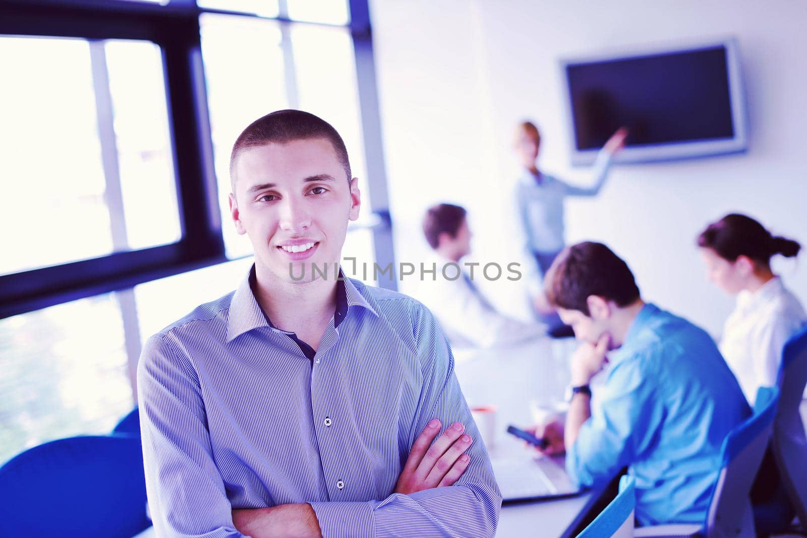 Portrait of a handsome young  business man  on a meeting in offce with colleagues in background