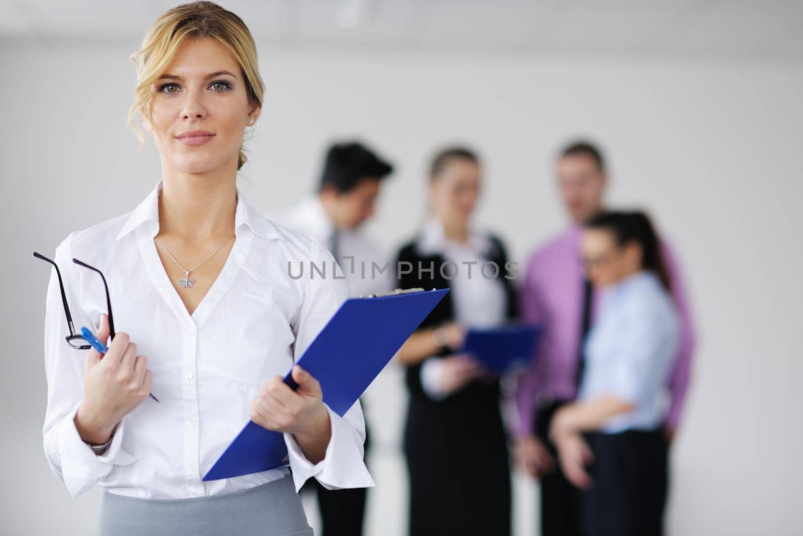 Successful business woman standing with her staff in background at modern bright office