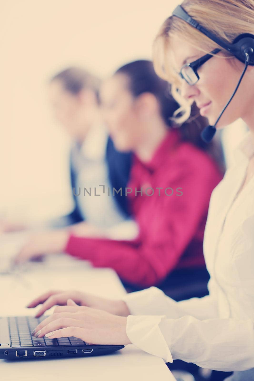 Pretty young business woman group with headphones smiling at you against white background