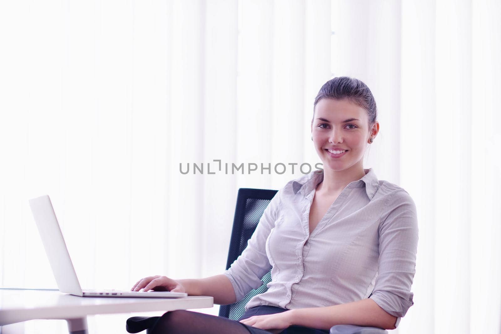 portrait of Young pretty business woman work on  notebook computer  in the bright modern office indoors