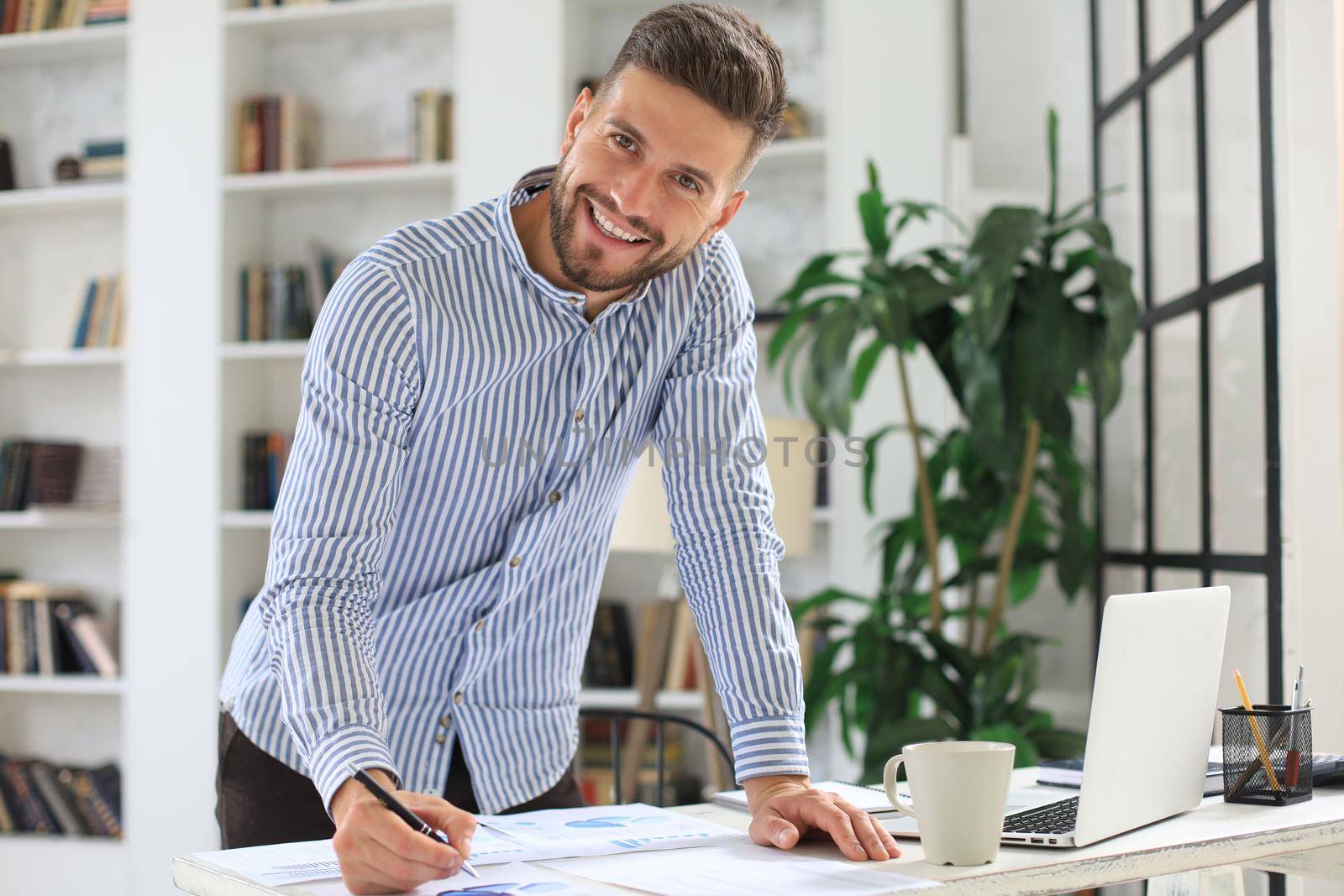Young modern business man analyzing data using laptop while working in the office