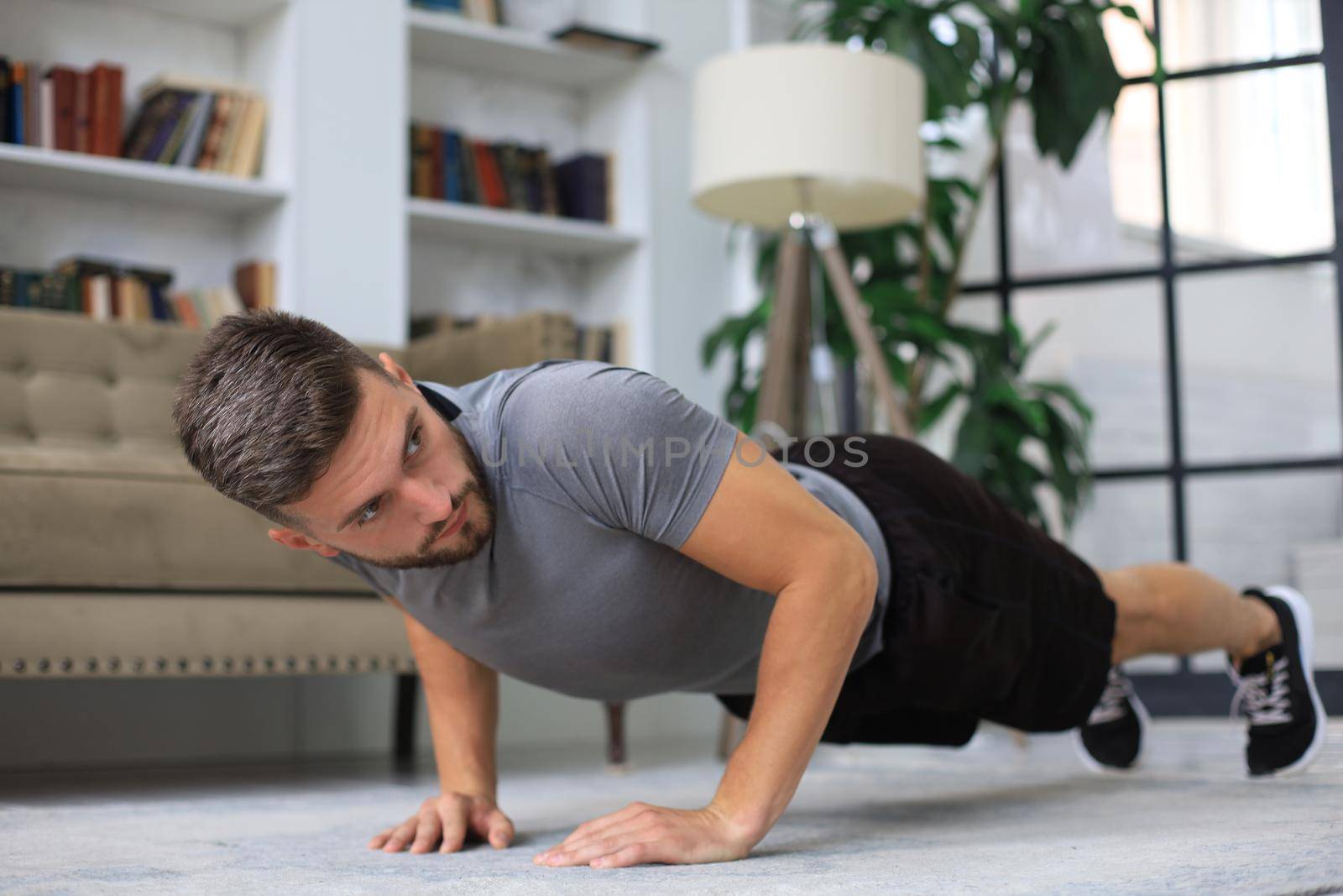 Handsome young man doing daily push up exercise at home. by tsyhun