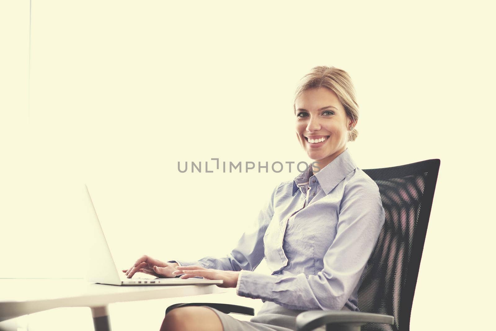 portrait of Young pretty business woman work on  notebook computer  in the bright modern office indoors