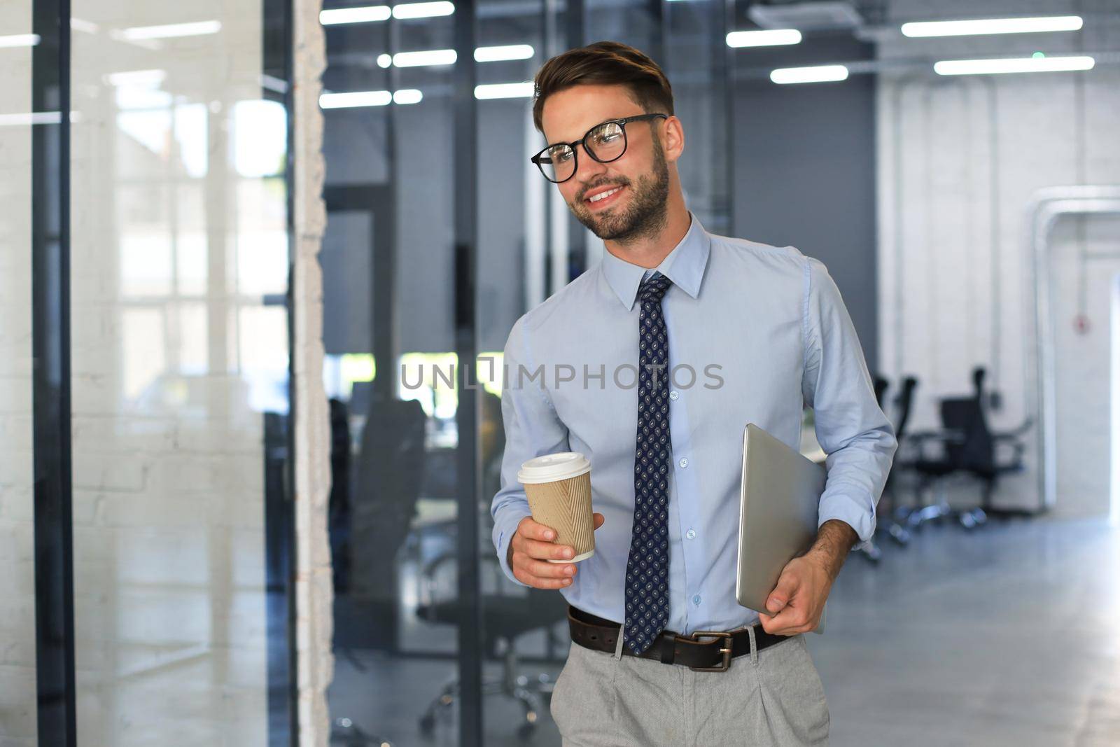 Businessman walking in office corridor with takeaway coffee
