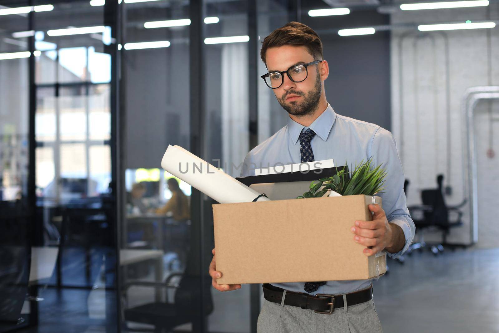 Sad dismissed worker is taking his office supplies with him from office