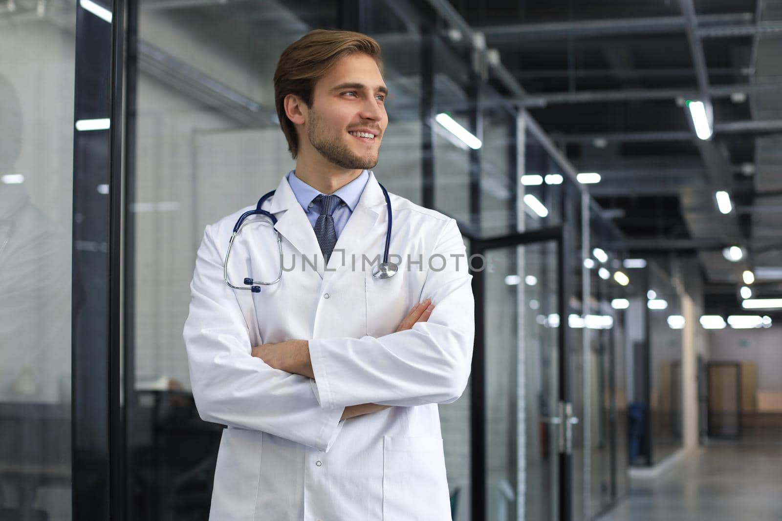 Portrait of doctor standing in hospital corridor wearing lab coat and stethoscope