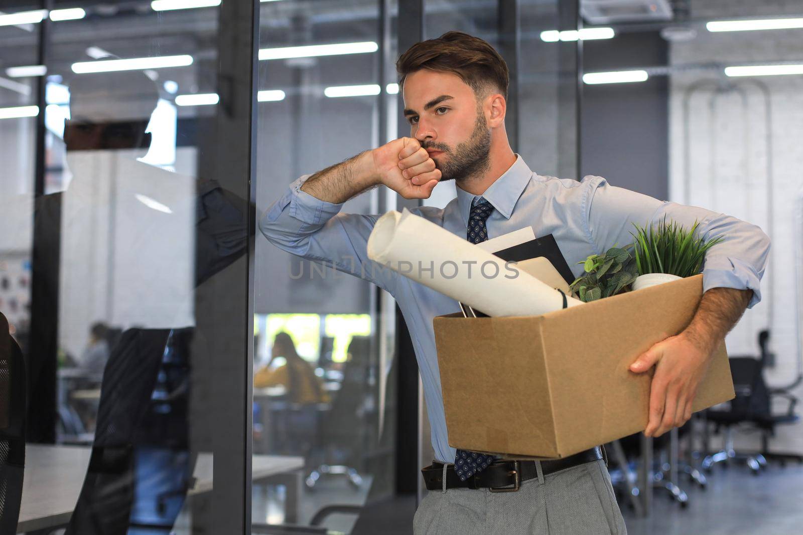 Sad dismissed worker is taking his office supplies with him from office