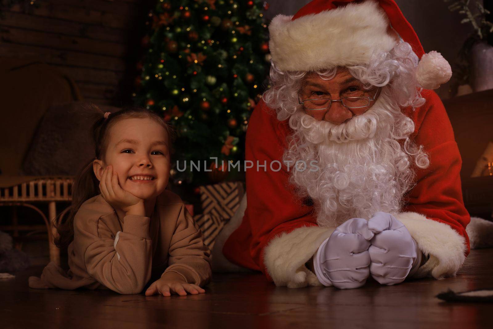 Santa Claus and child laying on floor at home. Christmas gift. Family holiday concept. by tsyhun