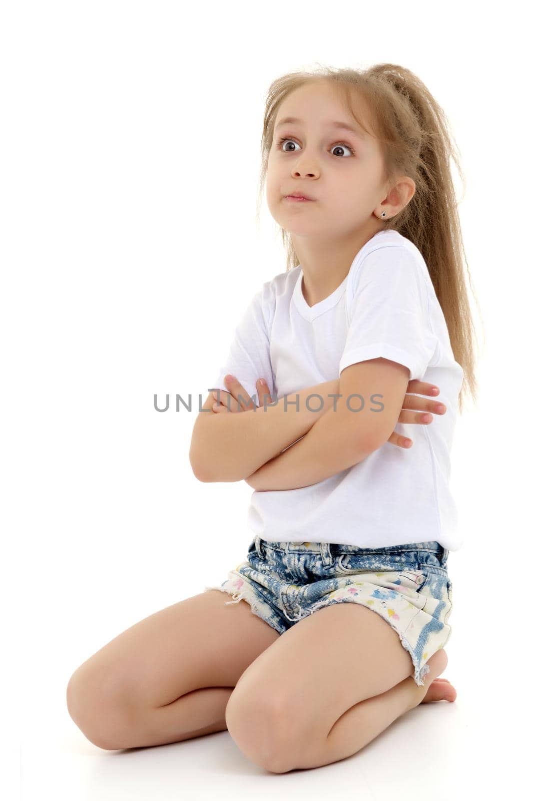 Beautiful little girl kneels in the studio on a white background. The concept of beauty and fashion, children's emotions. Isolated.