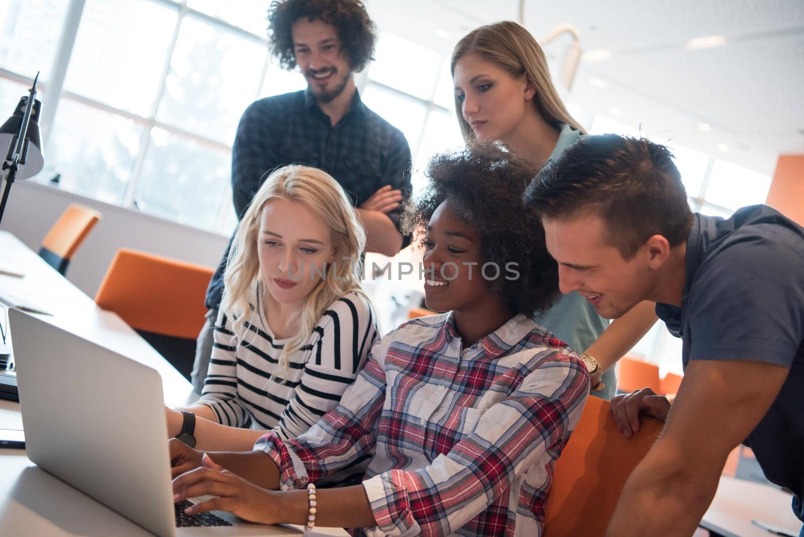 Multiethnic startup business team on meeting in modern bright office interior brainstorming, working on laptop