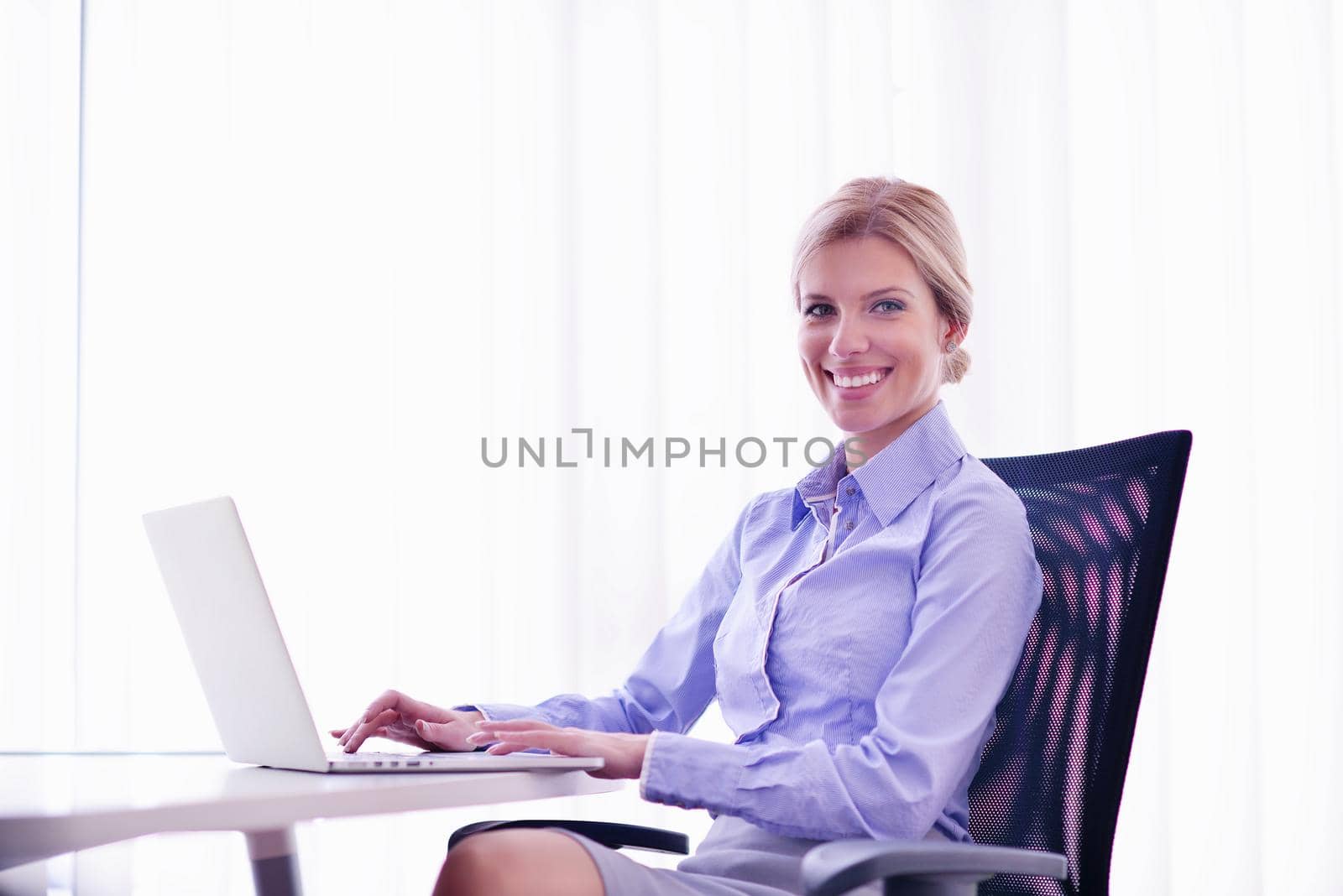 portrait of Young pretty business woman work on  notebook computer  in the bright modern office indoors