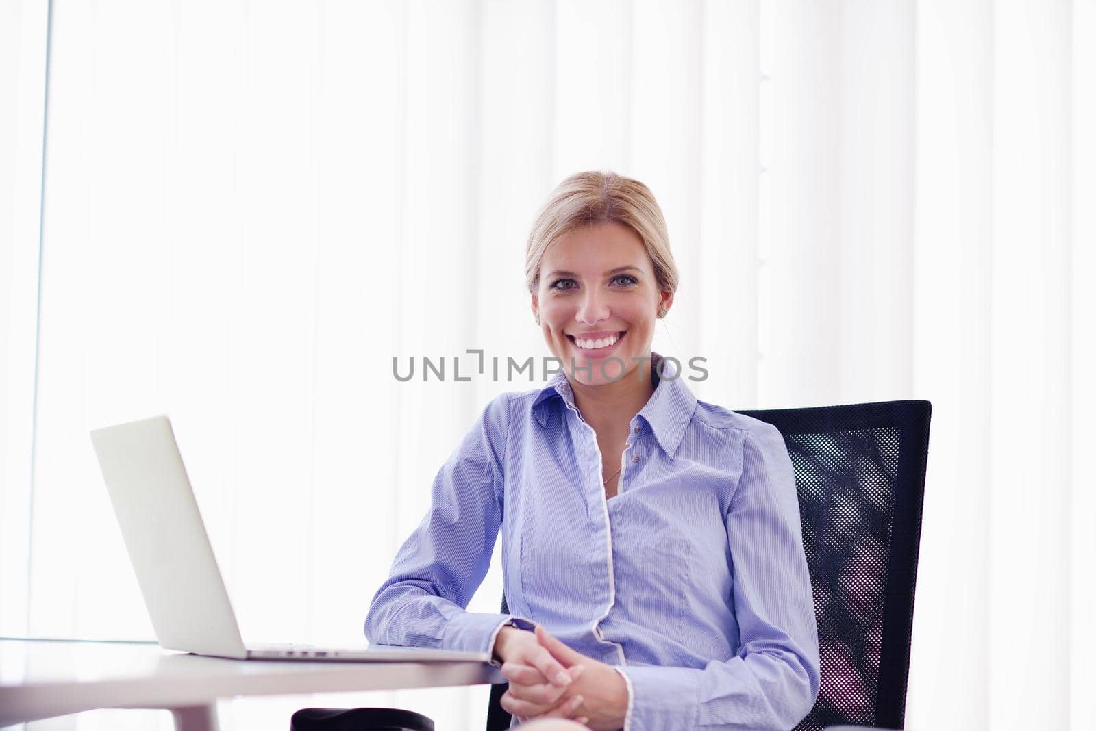 portrait of Young pretty business woman work on  notebook computer  in the bright modern office indoors